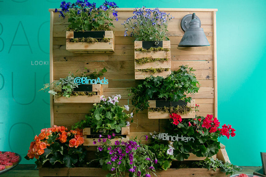 Wooden wall with flower arrangements installed in wooden flower boxes
