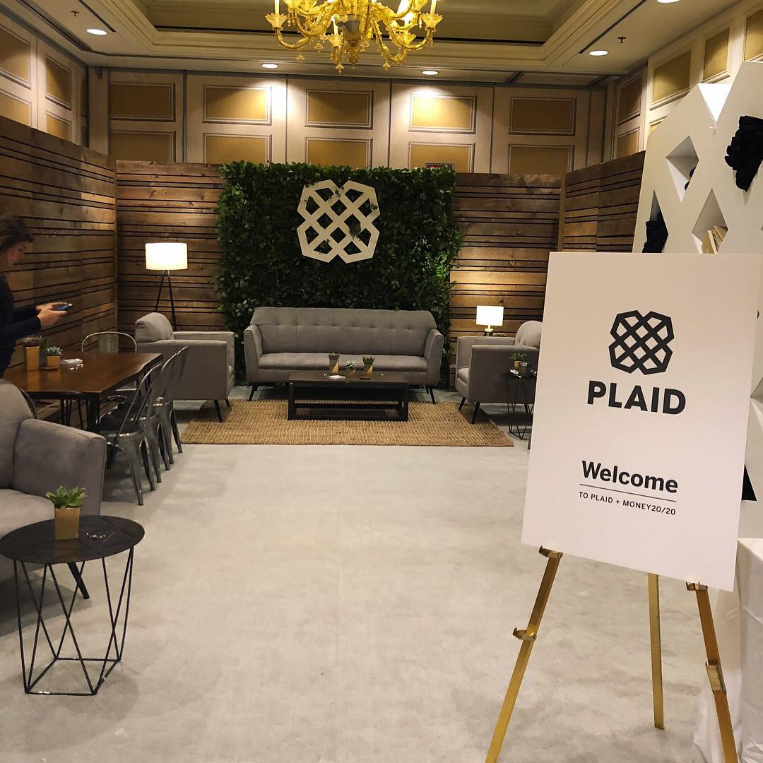 Plaid Money 2020 Event Pop-up room with grey furniture and greenery backdrop.