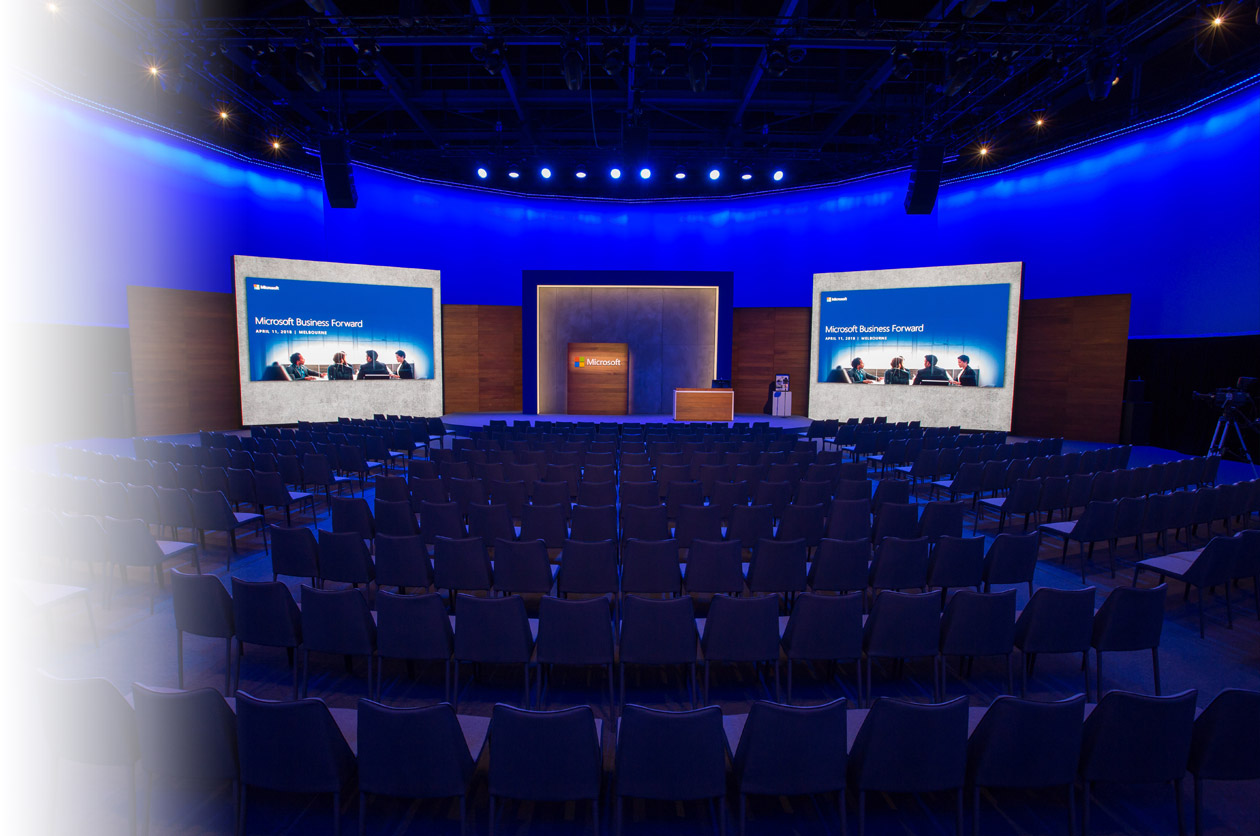 Large room with chairs in front of a stage with Microsoft branding.