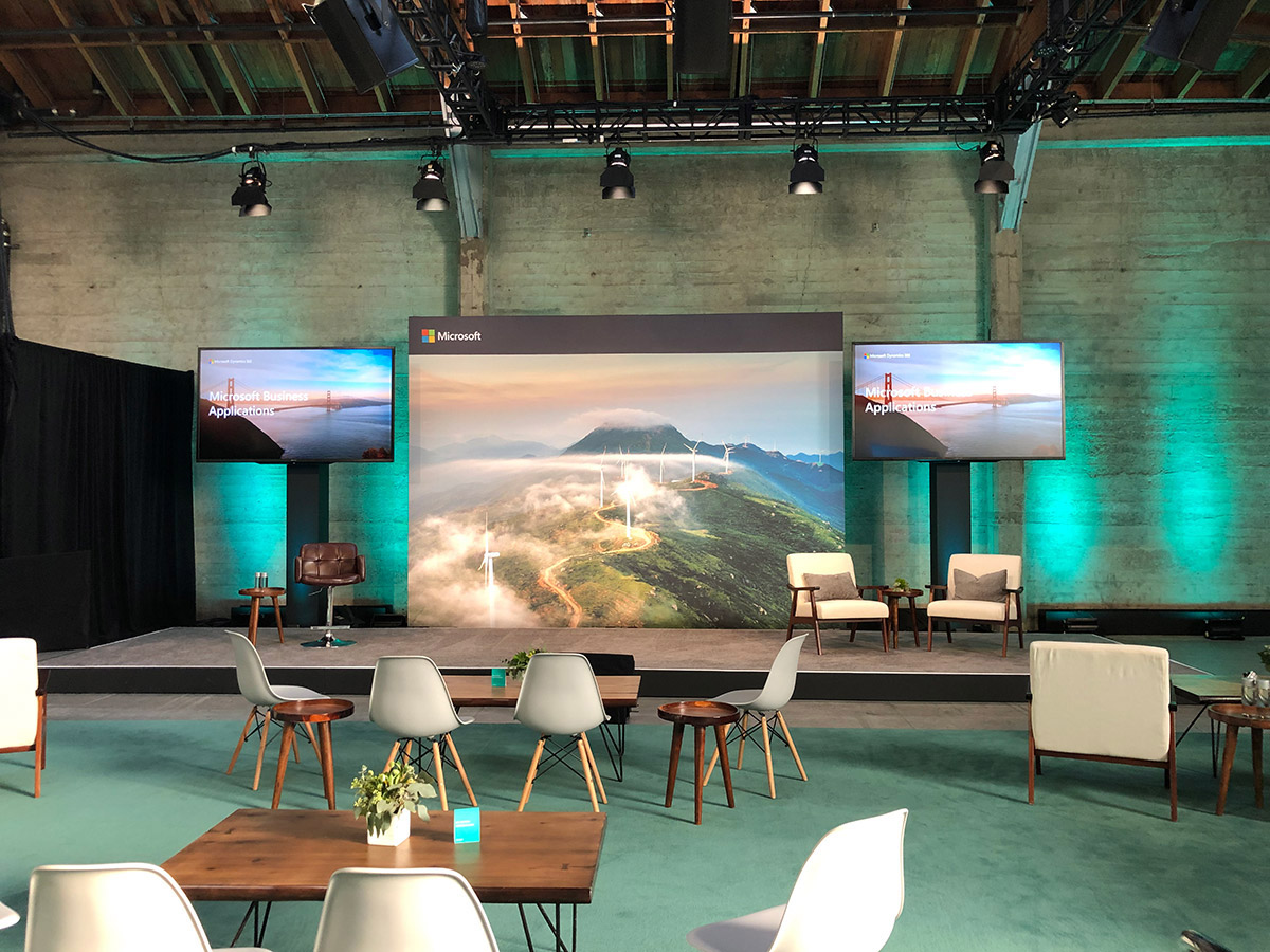 Large room with chairs and tables set in front of a Microsoft branded stage.